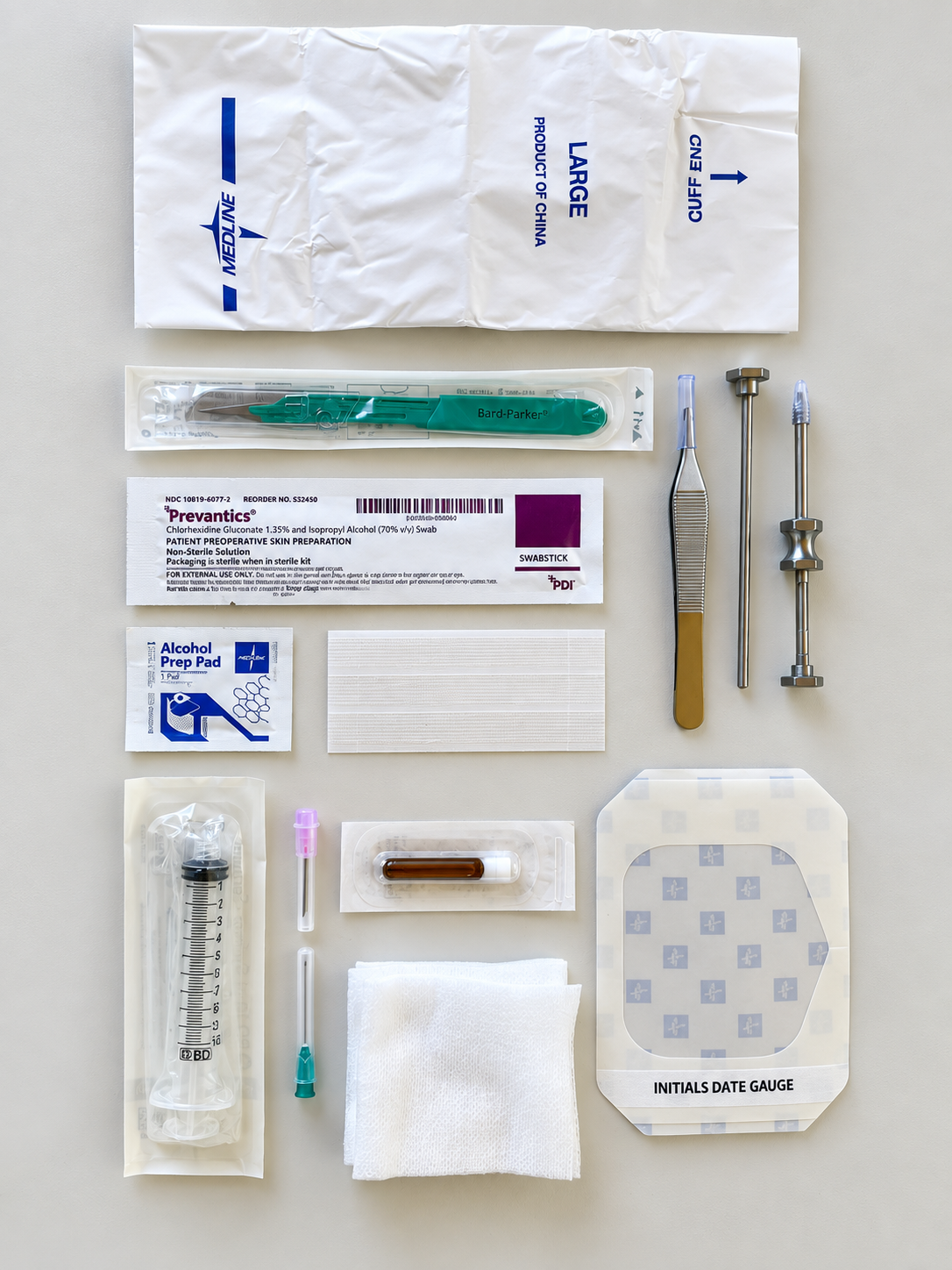 Medical sterile kit laid out: scalpel handle with blades, syringe, swabs, alcohol pad, gauze, and labels on a light background.